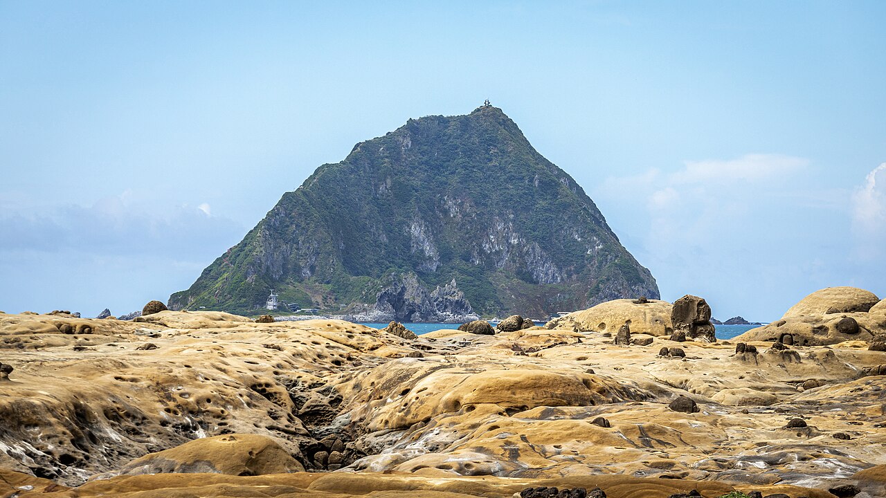 Formaciones de arenisca erosionada del geoparque de la isla de Heping, con la isla de Keelung al fondo